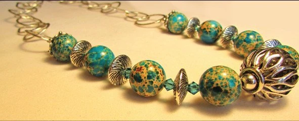 Close detail of green and gold patterned beads with sculpted metal spacers
